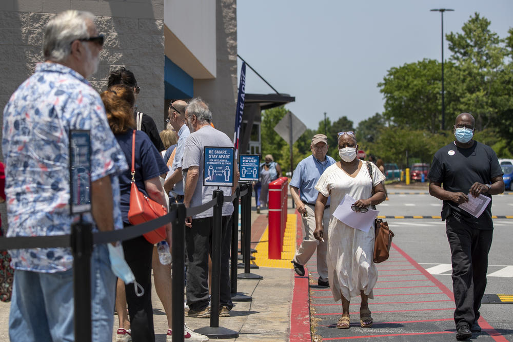 Voters (right) walk past a line of residents waiting to cast their ballot at the Gwinnett County Board of Voter Registrations and Elections in Lawrenceville, Ga., on May 18.