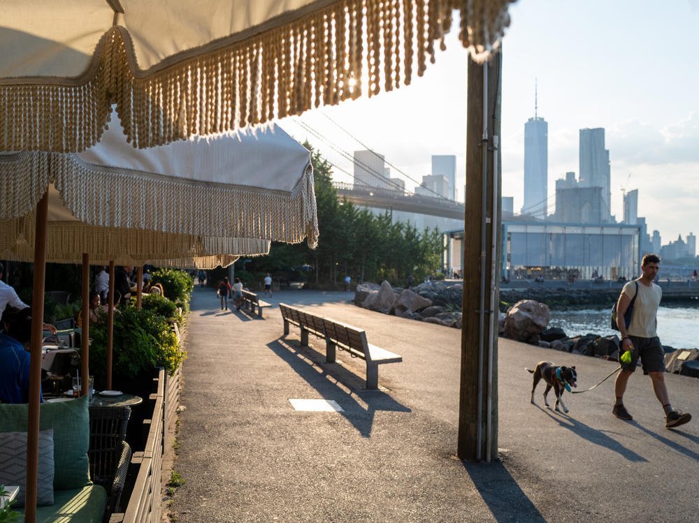 People walk along the East River in Brooklyn, New York, as temperatures reached into the 90s on Wednesday.