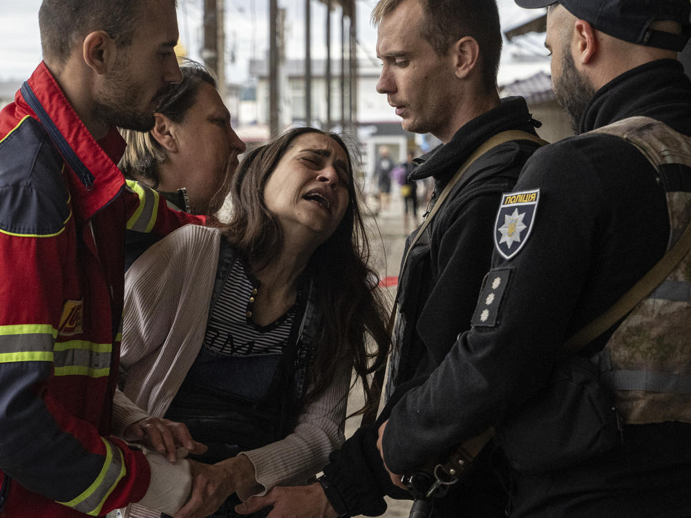 People try to console a woman named Sabina after her husband Artem Pogorelets was killed by Russian shelling in a market in Kharkiv, Ukraine, on Thursday.