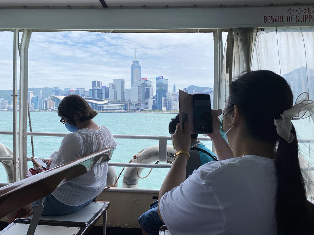 A passenger photographs Hong Kong's skyline while riding the Star Ferry.