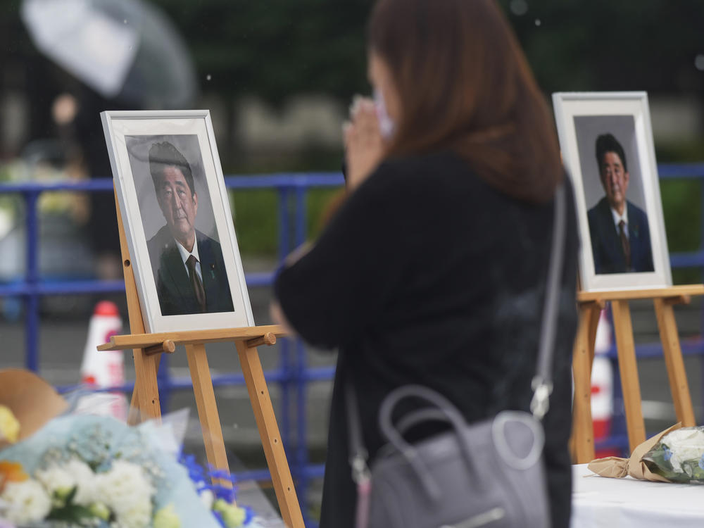 A woman prays after offering a bouquet of flowers at the memorial area set up for former Japanese Prime Minister Shinzo Abe.