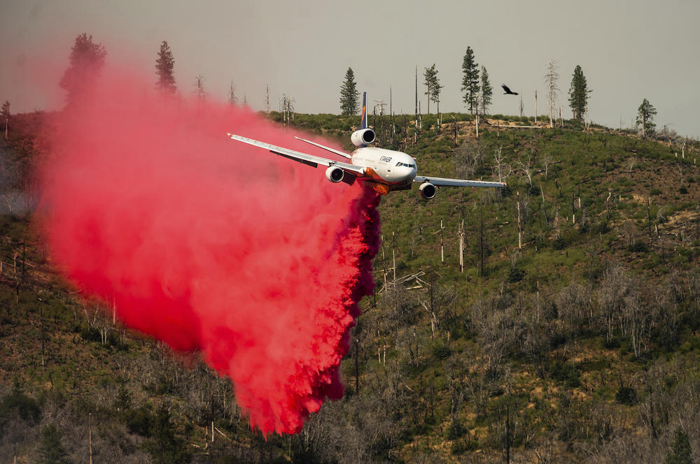 An air tanker drops retardant while trying to stop the Oak Fire from reaching the Lushmeadows community in Mariposa County, Calif., on Sunday.