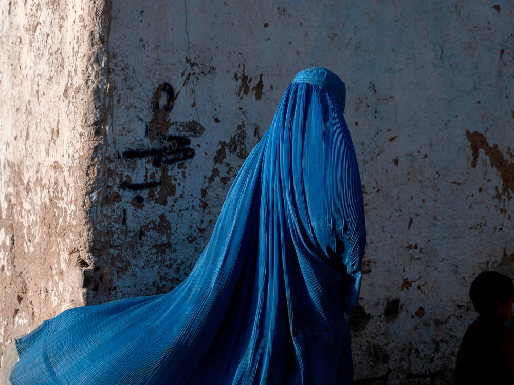 An Afghan woman walks with a child in Kabul, Afghanistan, April 28, 2022. A newly released report from Amnesty International, 