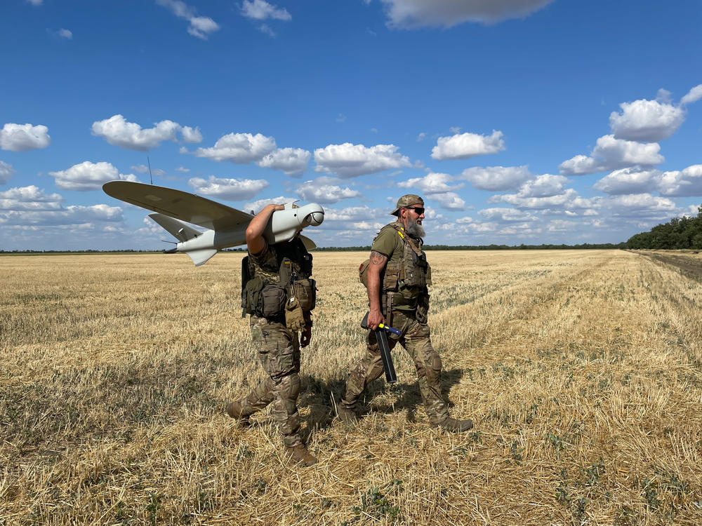Members of the Karlson drone unit collect one of their drones that just landed in a wheat field.