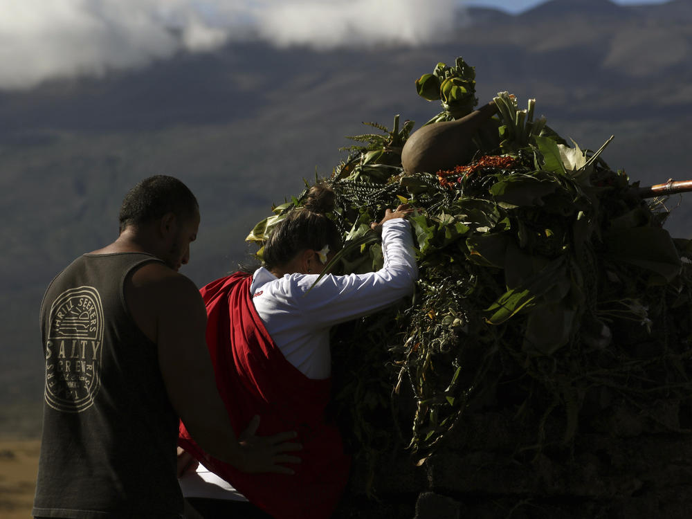 Native Hawaiian activists pray at the base of Mauna Kea, pictured in background, in 2019.