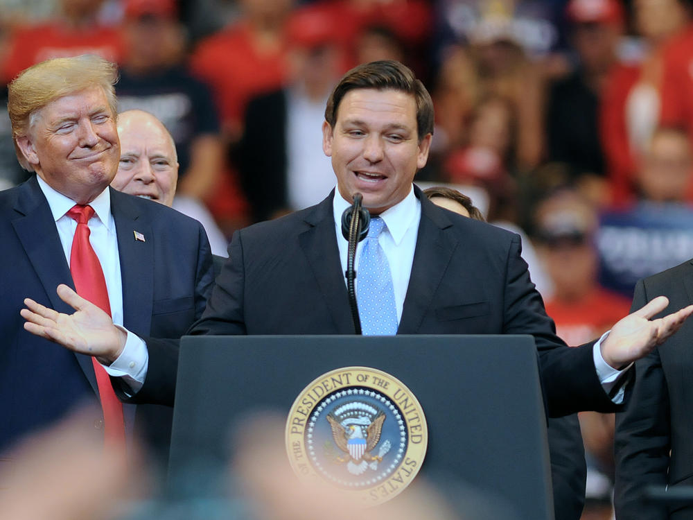 Then-President Donald Trump looks on as Florida Gov. Ron DeSantis speaks during the Florida Homecoming rally at the BB&T Center in 2019.