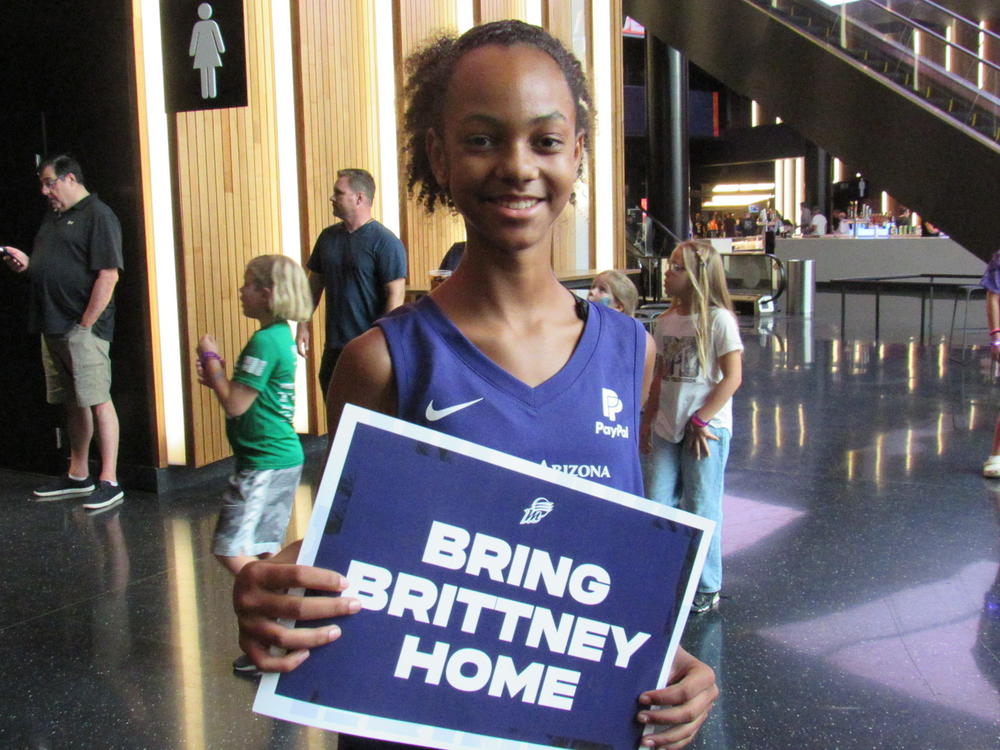 Zariyah Odom holds a sign calling for Griner to return home. Odom had just dropped off shoes for a charity effort that Griner has spearheaded.