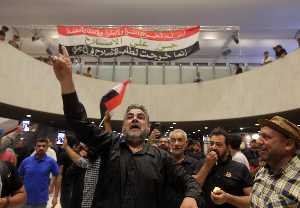 Iraqi protesters pose with national flags inside the Parliament building in Baghdad on Sunday.