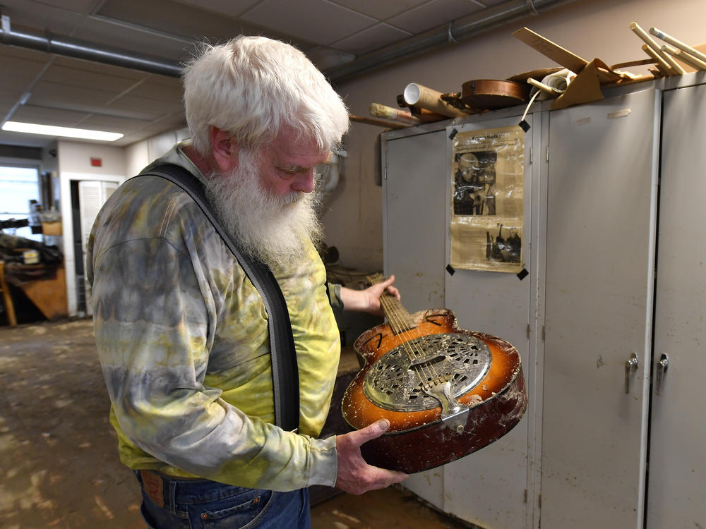 Paul Williams inspects the damage to a dobro guitar damaged by floodwaters from Troublesome Creek at the Appalachian School of Luthiery workshop and museum in Hindman, Ky., on Sunday.