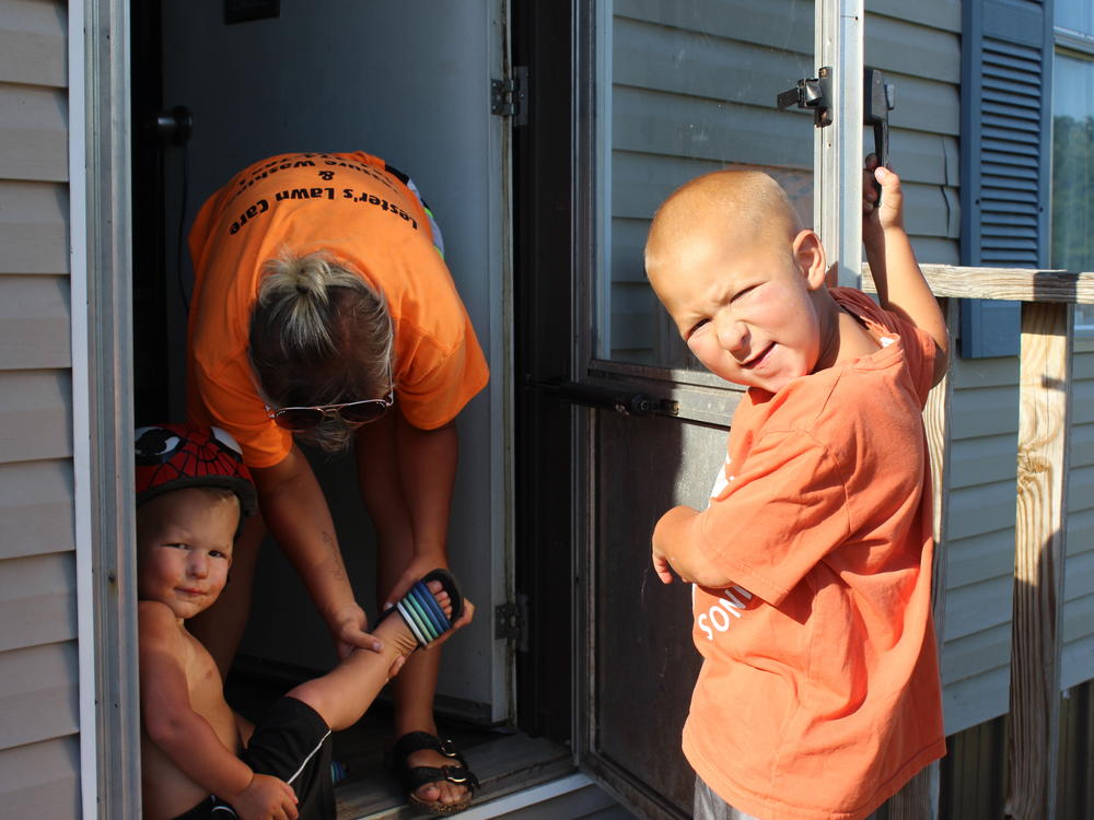 Katie Lester helps her two sons, Memphis (left) and Mason, put on shoes at their home in Belfast, Tenn. TennCare mailed the Lesters' Medicaid termination letter to a horse pasture, which is why the family did not realize their uninsured status.