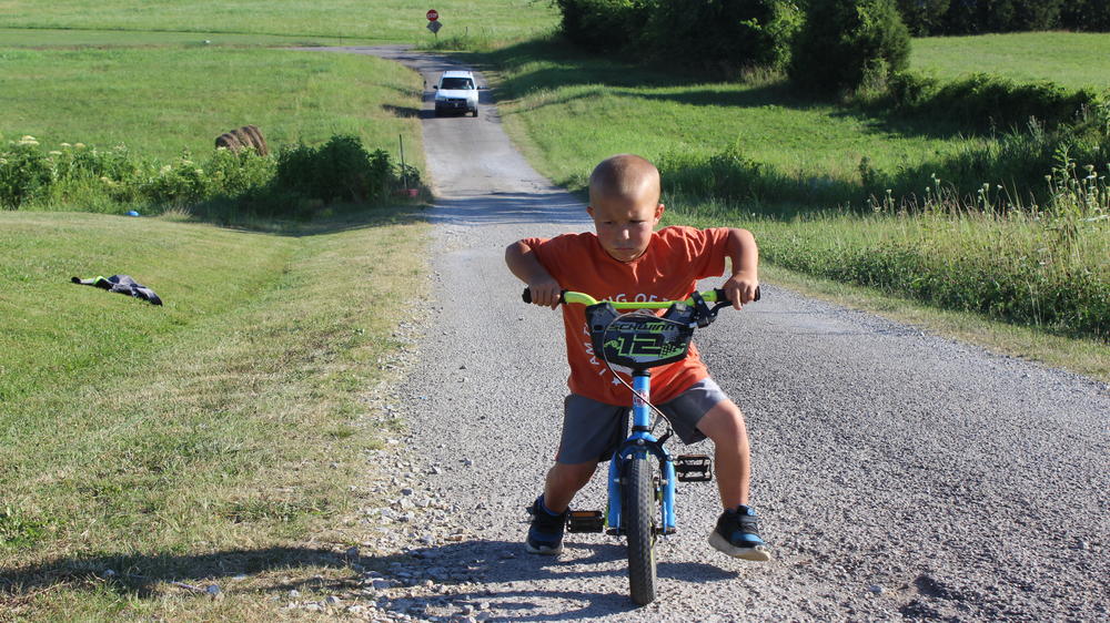 Mason Lester rides a bicycle on a country road in Belfast, Tenn., in June. Mason suffered a broken wrist and arm while uninsured.