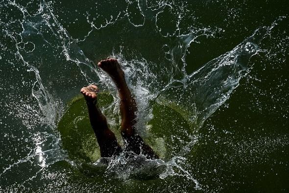 A boy jumps into Dal Lake to cool off on a hot summer's day in Srinagar, India, on July 18.