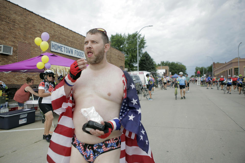 Brett Griffin of Oswego, Ill., eats popcorn as he walks down the streets of Schaller, Iowa, wearing an American flag and star-spangled speedo Tuesday, July 25. Griffin, who said this is his seventh time on the ride, said he and other members of his team, Giraffe's Up In The Air, wear the eye-catching costumes to draw attention to their fundraising efforts for children's cancer research.