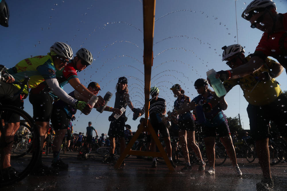 Riders fill up their water bottles at a sprinkler station set up along RAGBRAI's route Wednesday, July 28, in Whittemore, Iowa.