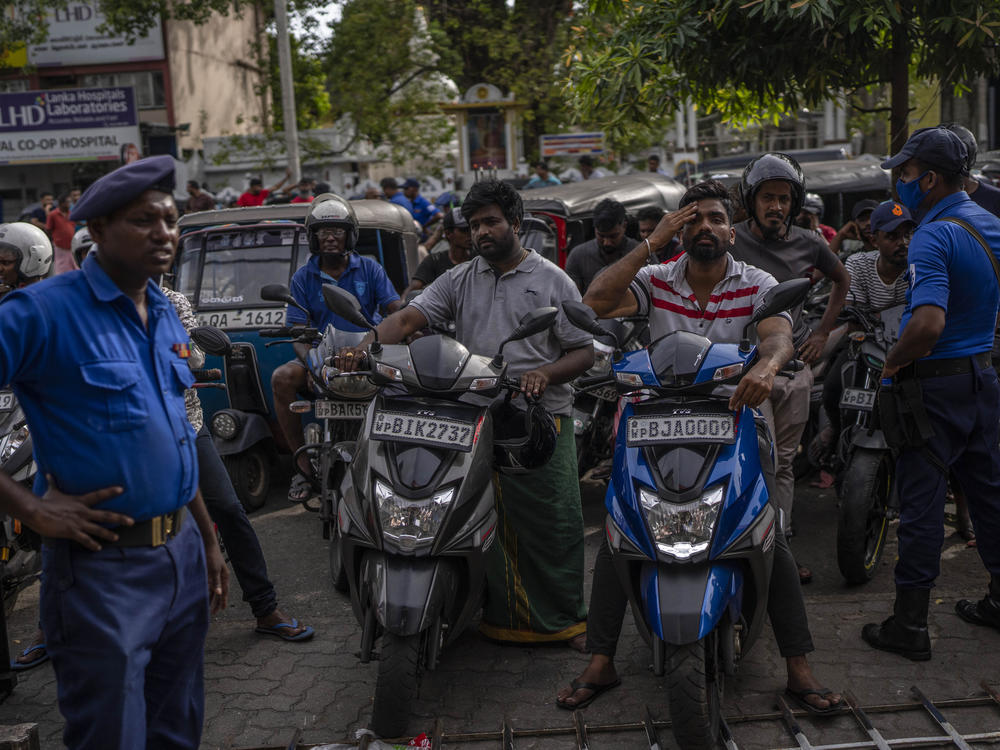 Police officers stand guard as people wait in queue to buy petrol at a fuel station, in Colombo, Sri Lanka, July 17, 2022.