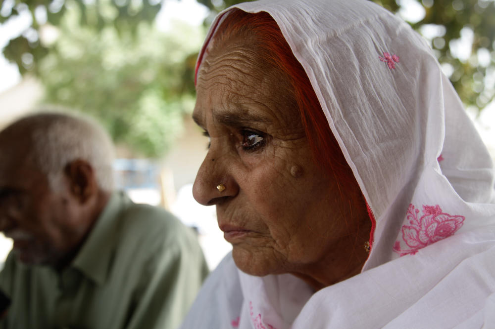 Sharifa Bibi sits in the garden of Mohammed Asghar's home, listening to how a man who she believes was her brother came to Pakistan decades ago, trying to find her and the rest of his family.