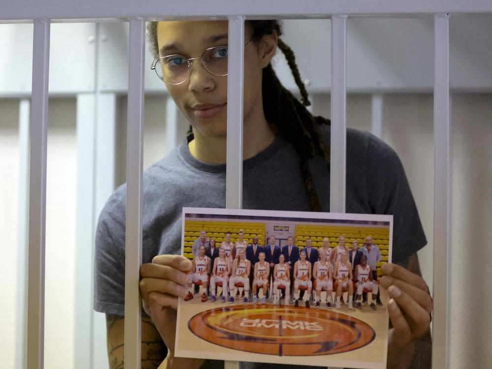Brittney Griner holds a picture of her Russian basketball team as she stands inside a defendants' cage before a court hearing in Khimki, outside Moscow, on Thursday.