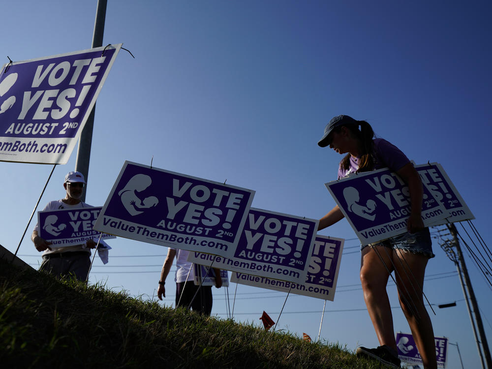 Supporters of a constitutional amendment about abortion in Kansas remove signs ahead of Tuesday's vote.