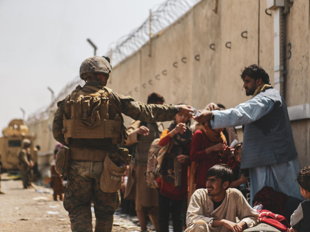 This handout image shows a Marine passing out water to evacuees during an evacuation at Hamid Karzai International Airport, Kabul, Afghanistan, Aug. 22.
