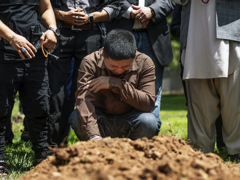 Altaf Hussain cries over the grave of his brother Aftab Hussein at Fairview Memorial Park in Albuquerque, N.M., on Friday, Aug. 5, 2022. A funeral service was held for Aftab Hussein, 41, and Muhammad Afzaal Hussain, 27, at the Islamic Center of New Mexico on Friday.