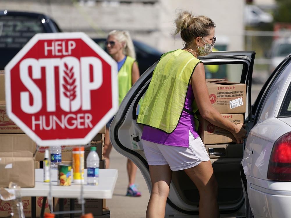 A volunteer loads a local resident's vehicle at a drive-up produce giveaway organized by a Des Moines food pantry on Aug. 28, 2020, in Des Moines, Iowa.
