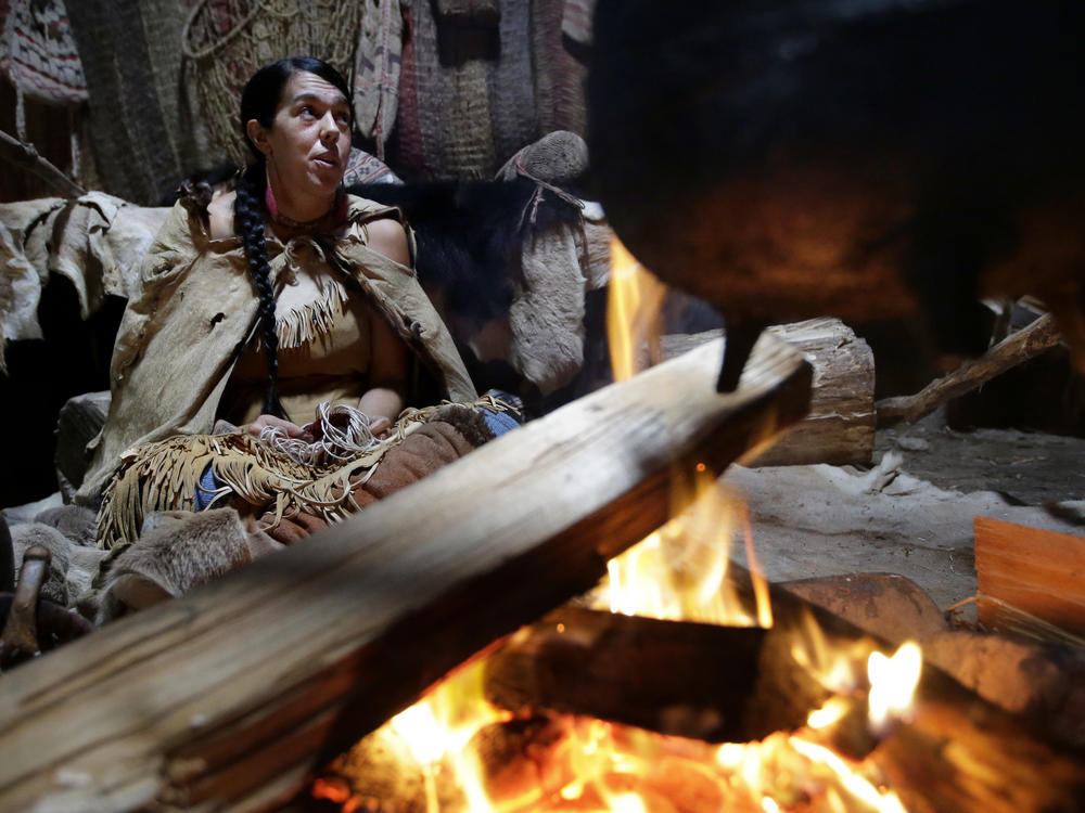 Mashpee Wampanoag Kerri Helme uses plant fiber to weave a basket while sitting next to a fire on November 15, 2018, at the Wampanoag Homesite at the Plimoth Patuxet Museums, in Plymouth, Mass.