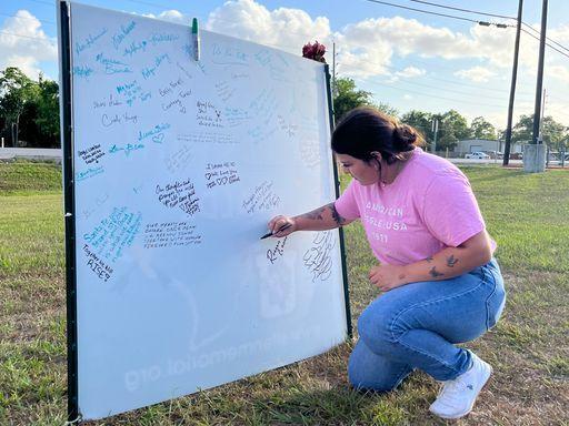 Reagan Gaona signs a tribute from students in Santa Fe, Texas, to those in Uvalde, where 19 students and two teachers were fatally shot.