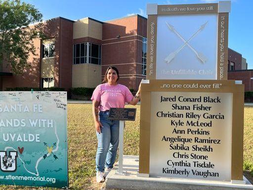 Reagan Gaona stands beside the Unfillable Chair memorial in front of Santa Fe High School in Texas. The memorial is dedicated to the eight students and two teachers killed in a May 2018 shooting. To the left is a sign displaying solidarity with Uvalde, Texas, a city that experienced a similar school shooting in May 2022.