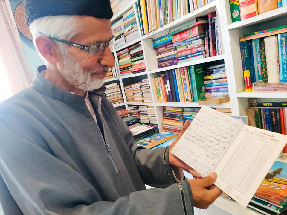 Zareef Ahmad looks at his notebook of tree notations in his home in Srinagar on May 11, 2022. He has planted hundreds of chinar trees over the years. 