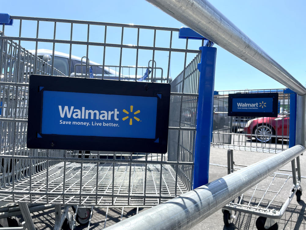 Shopping carts sit in the parking lot of a Walmart store in Rohnert Park, Calif., on Aug. 4. In a letter to shareholders, Walmart's CEO said its customers are spending less on clothing and other merchandise because food prices have continued to rise.