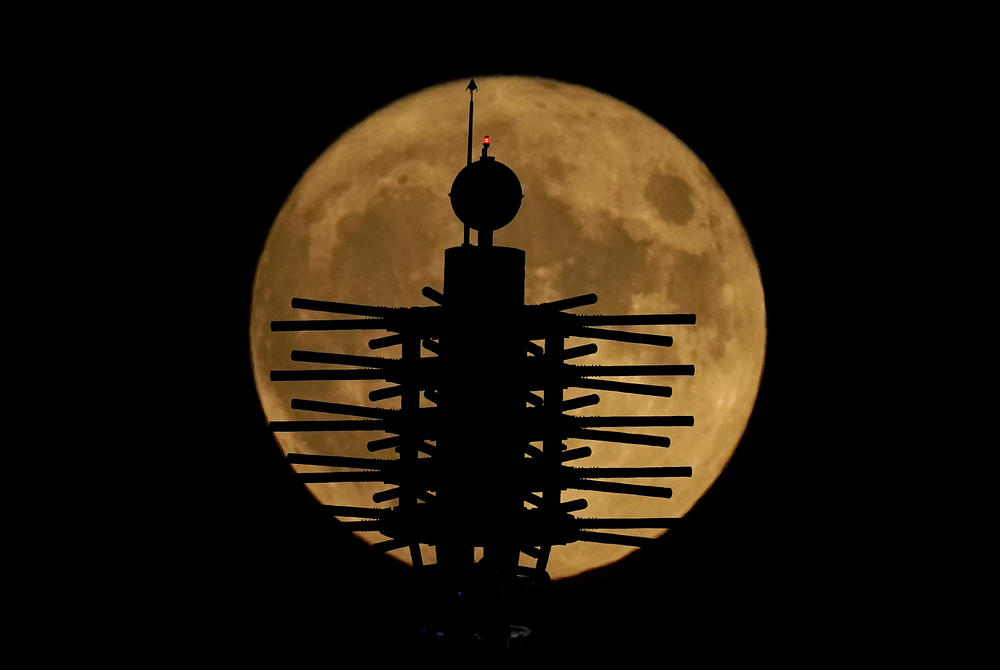 Kansas City, Missouri: A supermoon rises beyond artwork on top of a convention center.