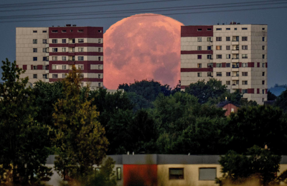 Frankfurt, Germany: The full moon sets behind apartment houses.