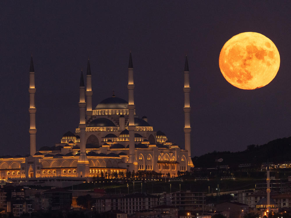Istanbul, Turkey: The Sturgeon full moon rises next to Istanbul's Camlica Mosque.
