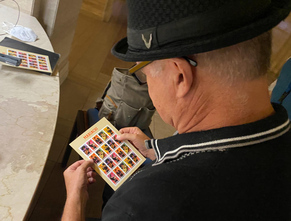 López signs a set of stamps at the museum.