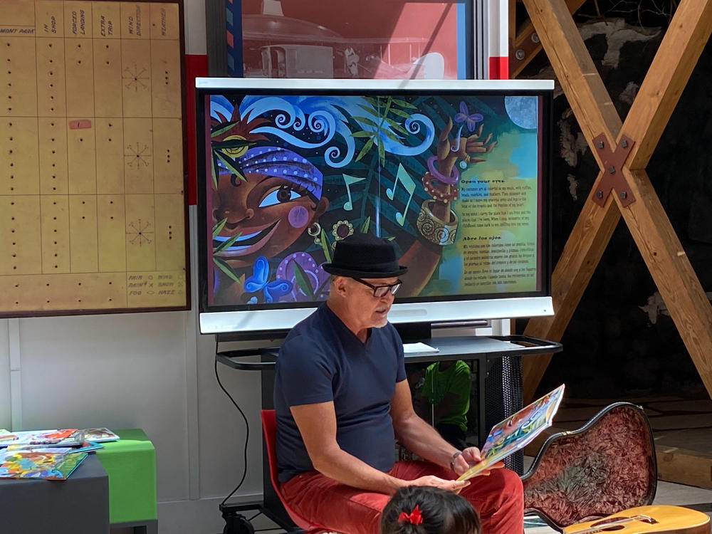 López reads books featuring his illustrations to a group of children.