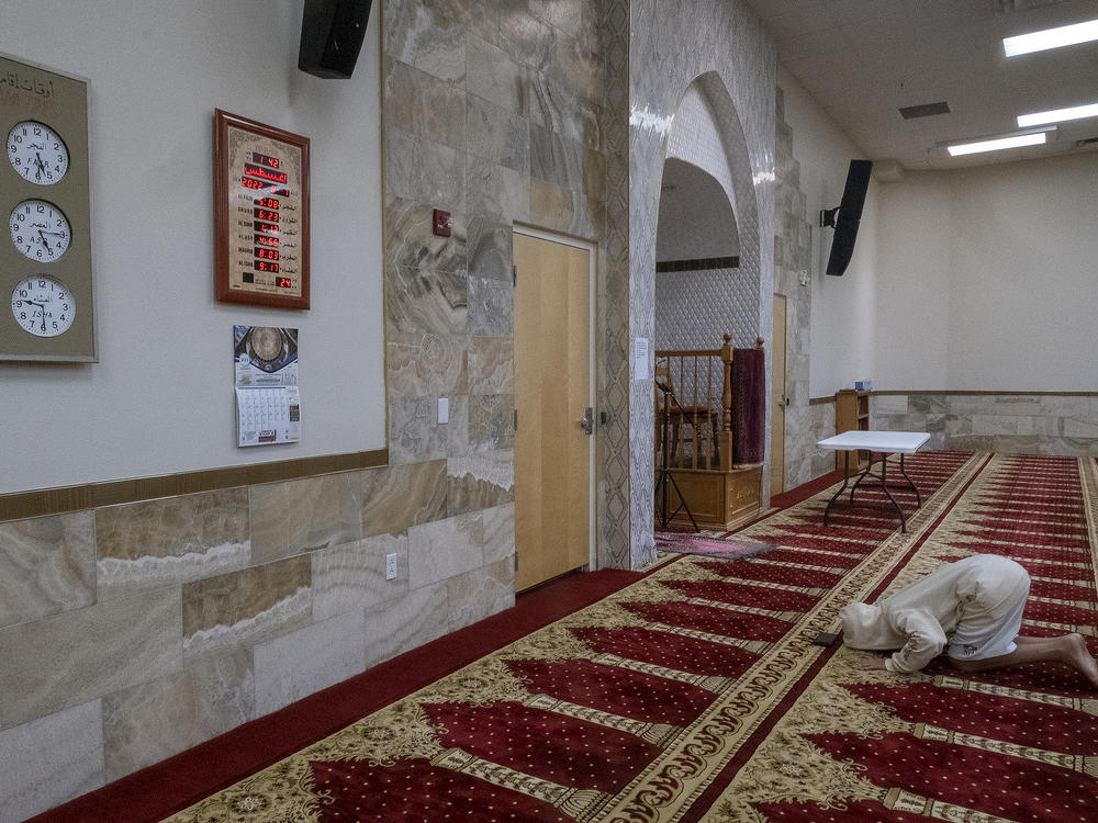 A young unidentified man bows during the Dhuhr afternoon prayer at the Islamic Center of New Mexico on Aug. 7, 2022, after the fourth Muslim man was killed in Albuquerque.
