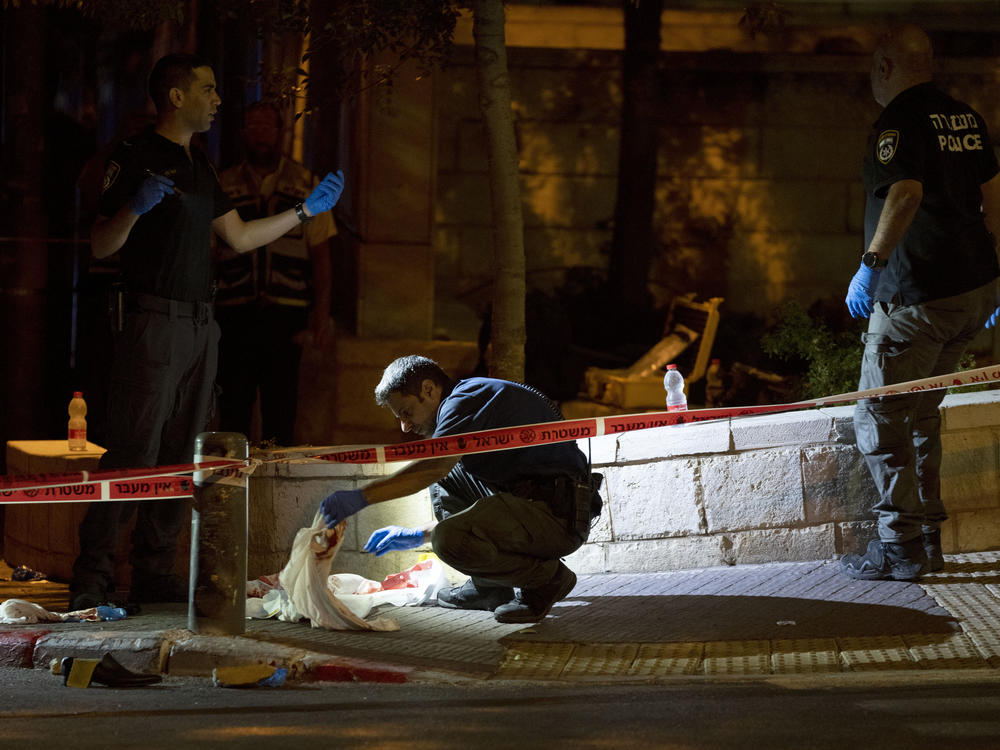 Israeli police crime scene investigators work at the scene of a shooting attack that wounded several Israelis near the Old City of Jerusalem, early Sunday, Aug. 14, 2022.