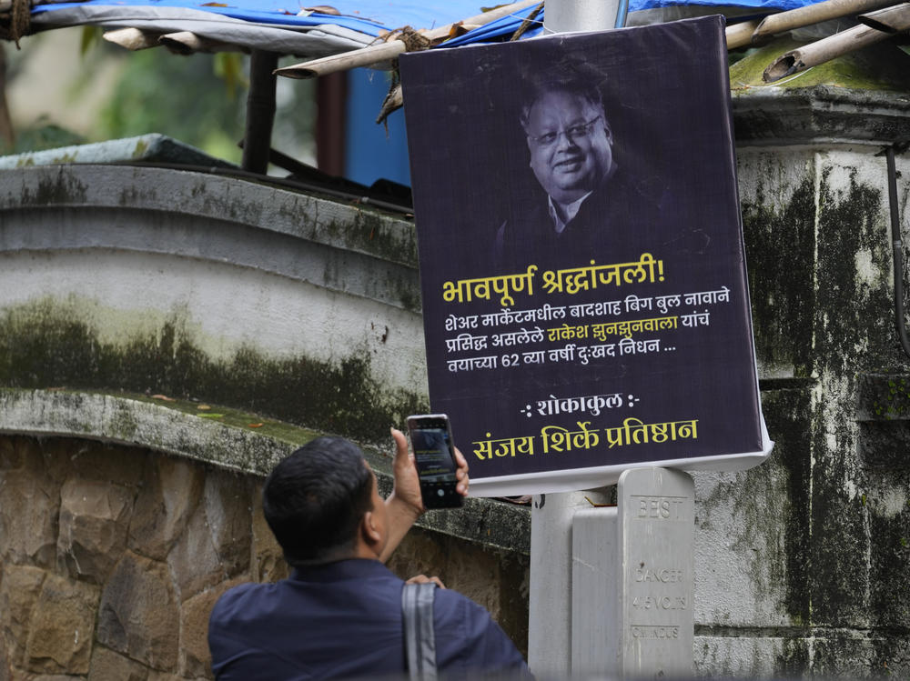 A man takes a picture of a poster paying homage to veteran stock market investor and Indian billionaire Rakesh Jhunjhunwala in Mumbai, India, on Sunday. Jhunjhunwala, died at the age of 62.