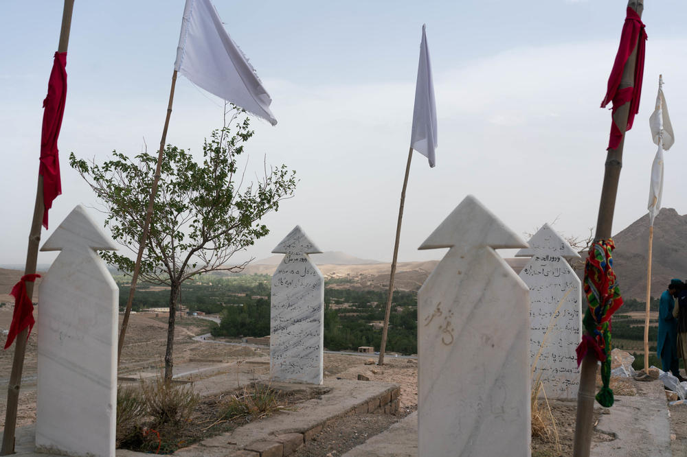 White flags stand over a shrine to the dead. Graves mark places for Mohammadi's brother and the late Taliban leader, Fazel Rabie.