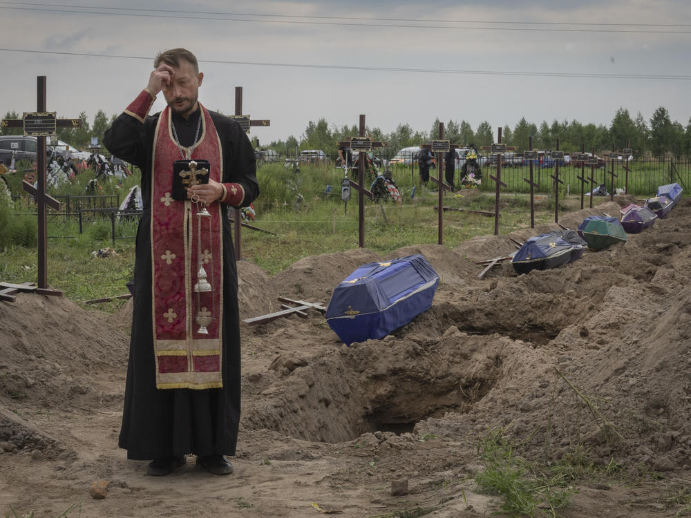 A priest prays for unidentified civilians killed by Russian troops in Bucha, on the outskirts of Kyiv, Ukraine, Aug. 11. Eleven unidentified bodies exhumed from a mass grave were buried in Bucha that day.