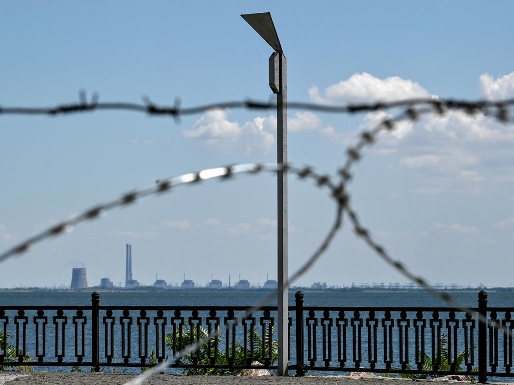 The Zaporizhzhia nuclear power plant in Ukraine's Enerhodar, Zaporizhzhia region, is seen through barbed wire on the embankment in Nikopol, Dnipropetrovsk region, central Ukraine, on July 20. Russian soldiers have been shelling Nikopol from the premises of the nuclear power plant.