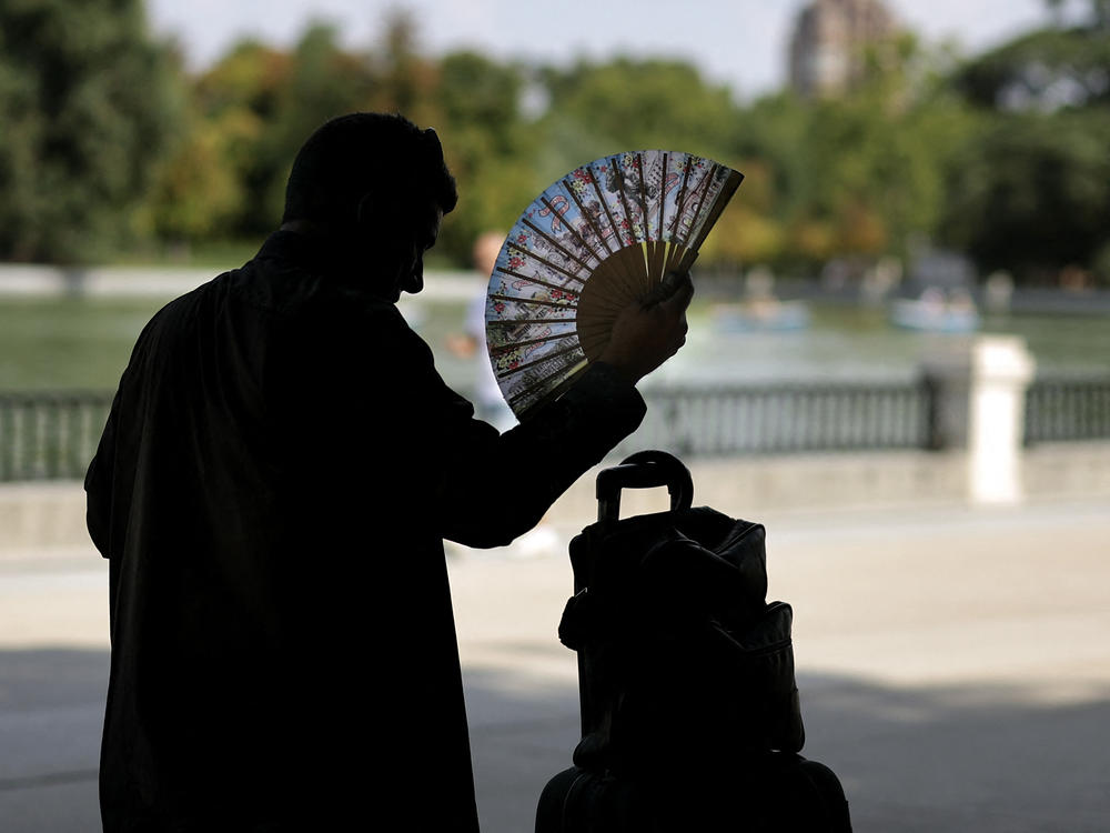 A man uses a hand fan in a park in central Madrid during a heat wave.