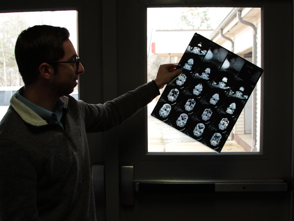 Braden Health's Kyle Kopec holds up a sample of diagnostic images left behind at an abandoned hospital they're taking over. They have to figure out what to do with old medical records stacked in boxes.