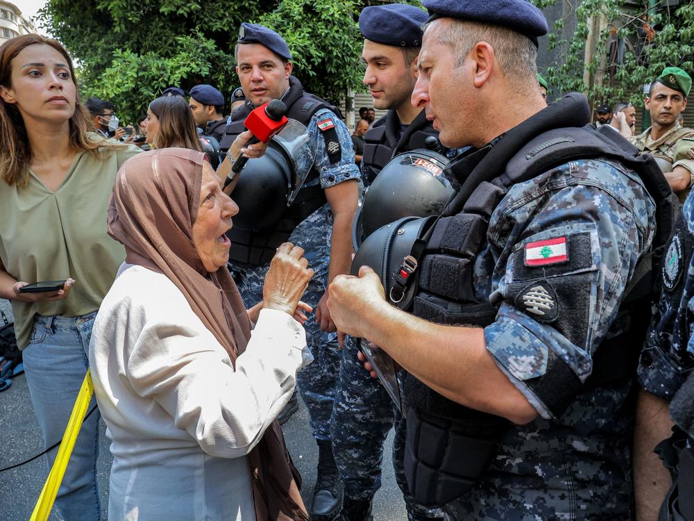 An angry bank client speaks with security forces outside the bank in Beirut on Thursday.