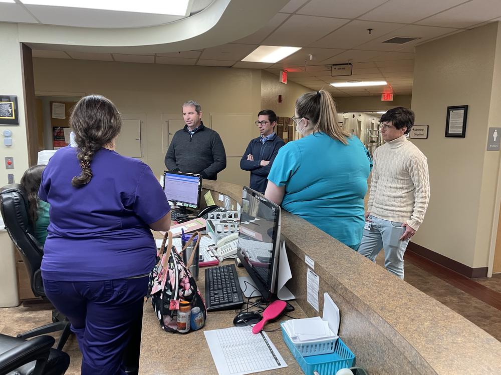 Dr. Beau Braden (left) and Kyle Kopec talk to staffers gathered at the nurse's station inside Houston County Community Hospital in Erin, Tennessee. Braden Health bought the facility for $20,000 ― a price that is mostly paying for the one piece of medical equipment deemed to have any value, a 2016 ambulance with 180,000 miles.