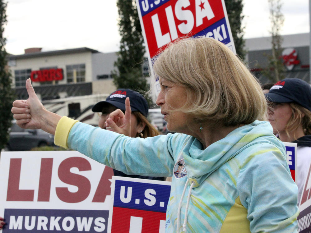 U.S. Sen. Lisa Murkowski, an Alaska Republican, flashes a thumbs up to a passing motorist while waving signs Tuesday in Anchorage.