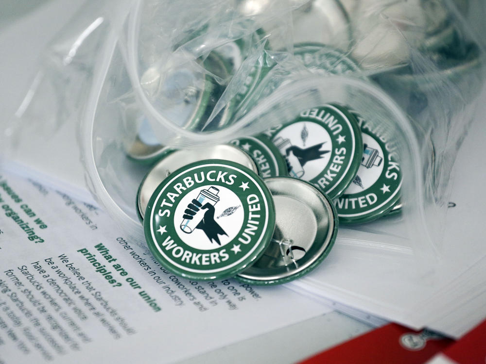 This file photo shows pro-union pins sitting on a table during a watch party for Starbucks' employees union election.