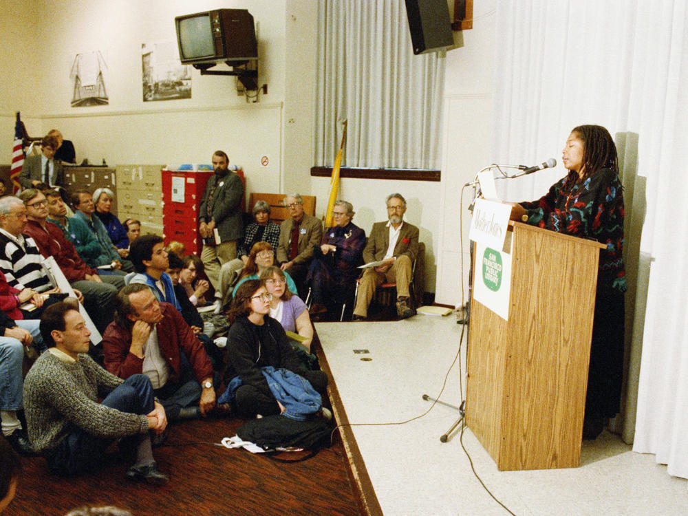 In 1989, after Iran's religious leader, Ayatollah Ruhollah Khomeini, issued a fatwa calling for the death of author Salman Rushdie, readings of his works were organized around the United States. At this one in San Francisco, novelist Alice Walker reads aloud from Rushdie's <em>The Satanic Verses</em>.