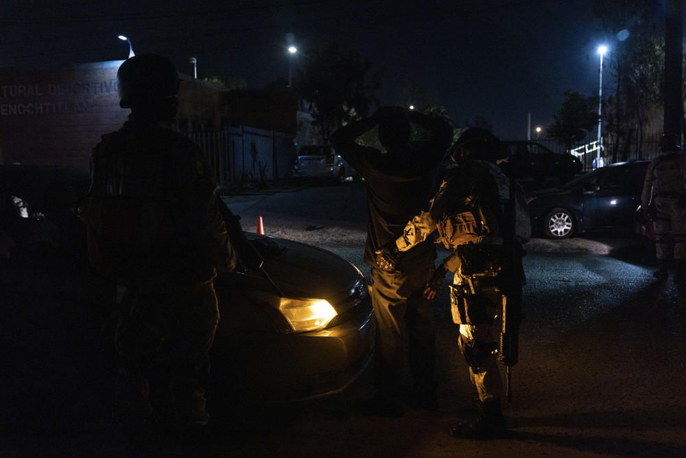 A member of the National Guard pats down a driver who was stopped at a checkpoint in the Gran Tenochtitlan neighborhood in Tijuana.