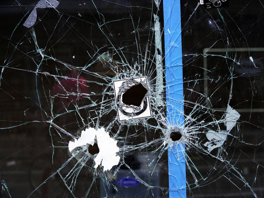 Bullet holes from a prior shooting are still visible in a storefront window at the scene of a fatal overnight shooting on South Street in Philadelphia on June 5, 2022.